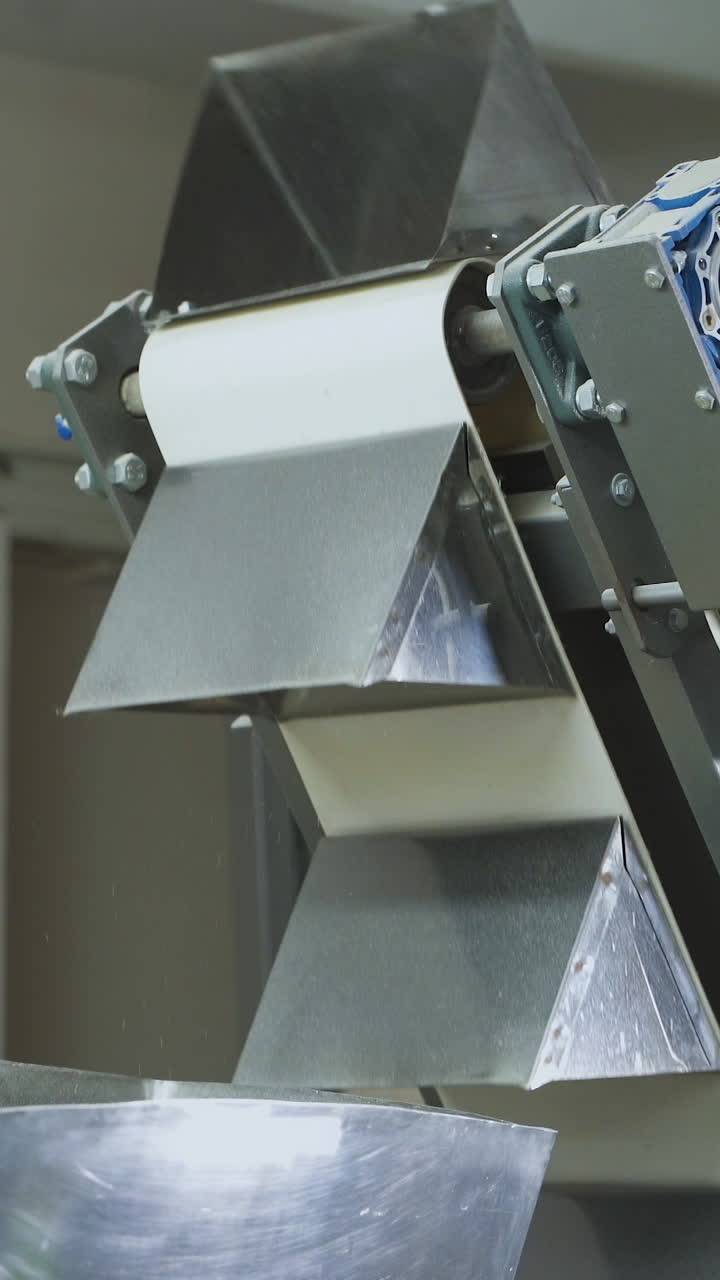 Feeding conveyor for bulk products. Automatic belt conveyor at a food factory. Production of corn snacks. Vertical video