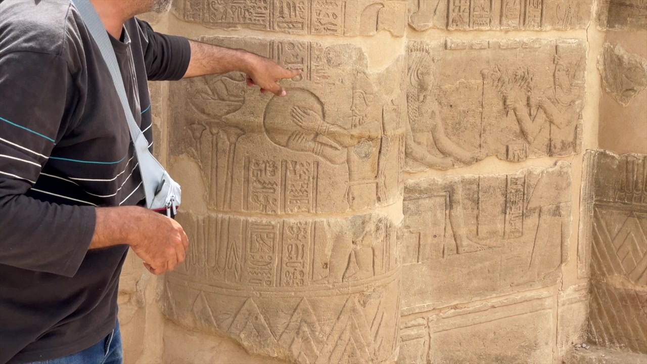 Homem apontando para hieróglifos egípcios no Templo de Ísis. Hieróglifo da civilização egípcia sendo mostrado por um egiptólogo no templo de Philae. Egiptologia e arqueologia egípcia e interpretação