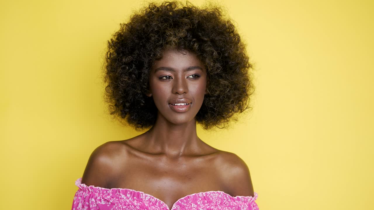 mujer sonriente en vestido rosa con afro
