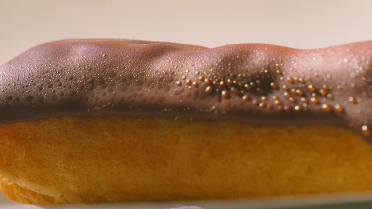 Close Up Sunlight Lit Pan Across Eclair Topped with Chocolate and Puff Pastry Filled with Whipped Cream. Traditional French Dessert Ready to Eat and Enjoy. Food Photography