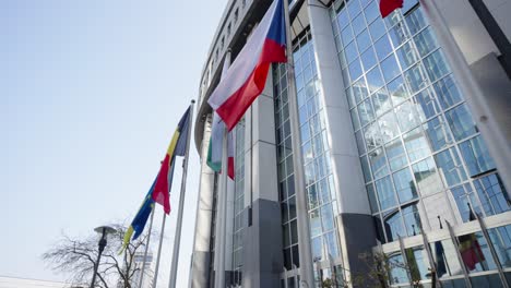 toma cinematográfica de banderas de países europeos ondeando frente al edificio del parlamento en bruselas, bélgica