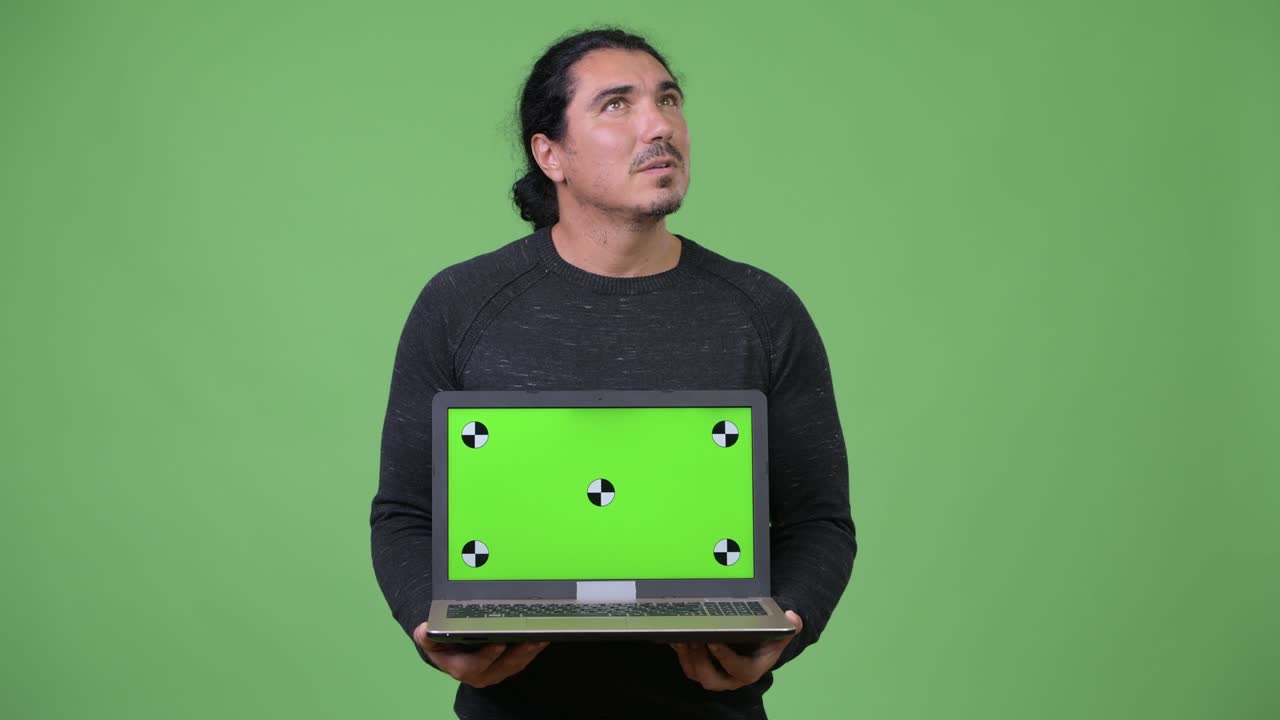 Happy handsome man thinking while showing laptop