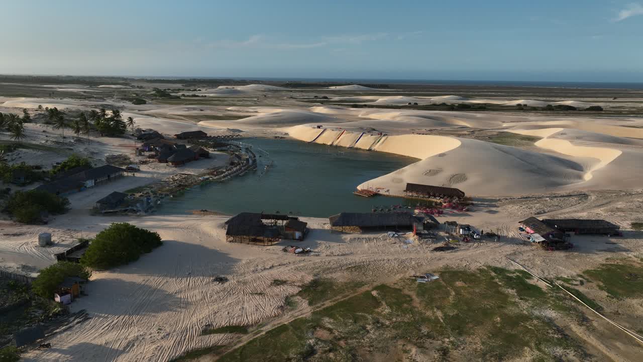 Aerial pan shot of tourists at Lencois Maranhenses with multiple restaurants and hotels for visitors during noon in Brazil