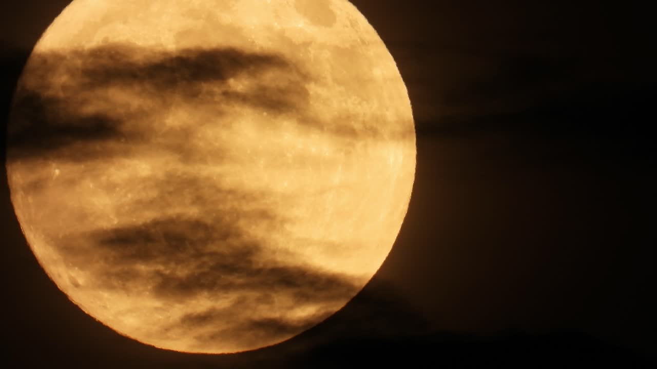 Dark Clouds Crossing Against Huge Yellow Moon Glowing In The Night Sky