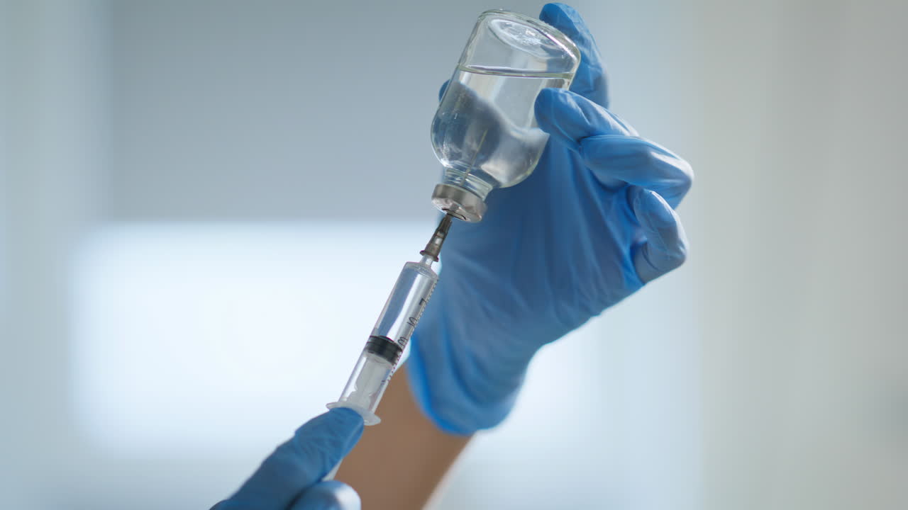 Nurse hands preparing vaccine dose for injection closeup. Doctor filling syringe