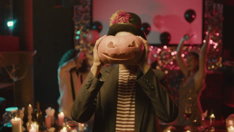 young man holding a pumpkin in front of his face.