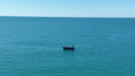 Eine-Einzelne-Person-Zieht-Schlange,-Während-Sie-Auf-Einem-Boot-Im-Offenen-Meer-Steht