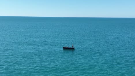 una persona solitaria hace fila mientras está de pie en un bote en el océano abierto