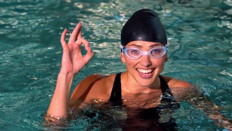 Fit-female-swimmer-showing-ok-sign-in-the-swimming-pool
