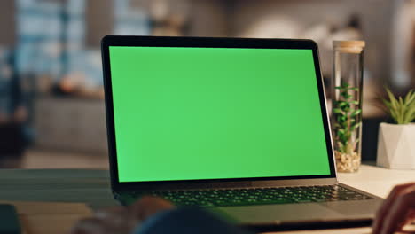 hombre de negocios de primer plano haciendo una llamada de video en una computadora de pantalla verde en la oficina nocturna