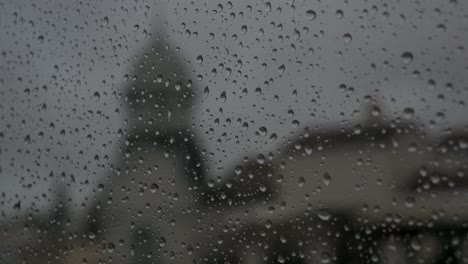 a close-up and narrow focus view of rainy glass as rain drops are seen on a window