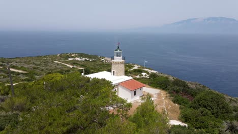 white lighthouse built on the top of a mountain facing the sea and the greek island of kefalonia