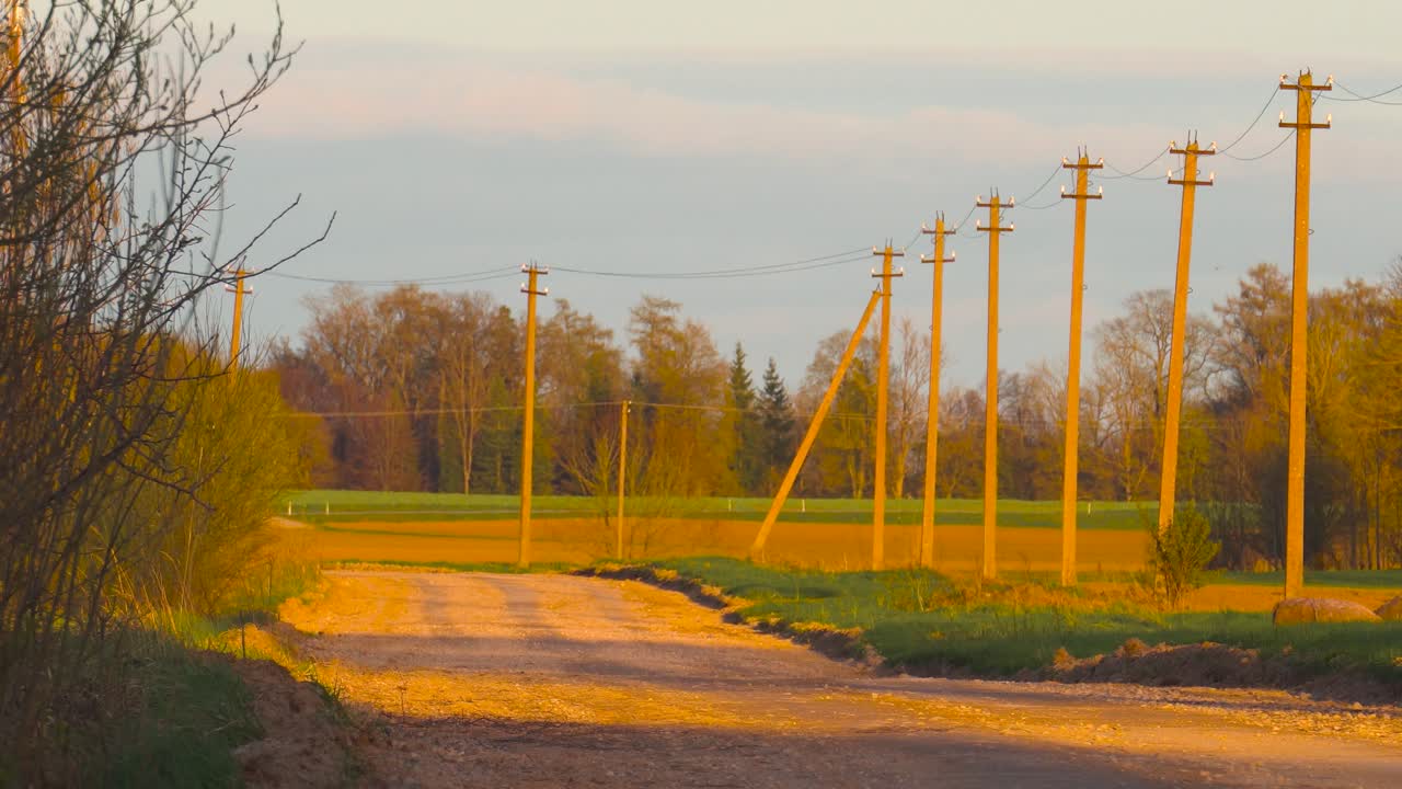 황금 시간 동안 전선이 으로 놓인 빈 시골 자갈 도로