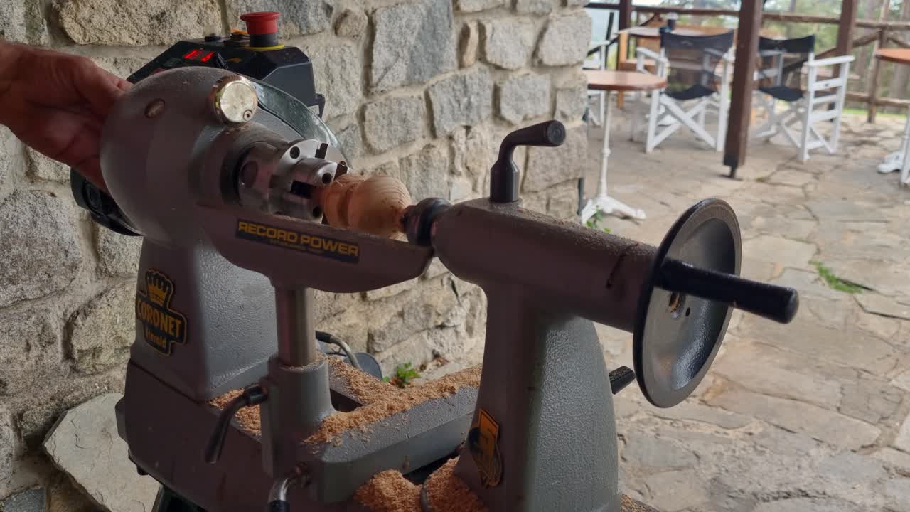 Close-up of a craftsman at a mountain workshop in Greece, carefully turning a small wooden toy on a lathe with traditional hand tools