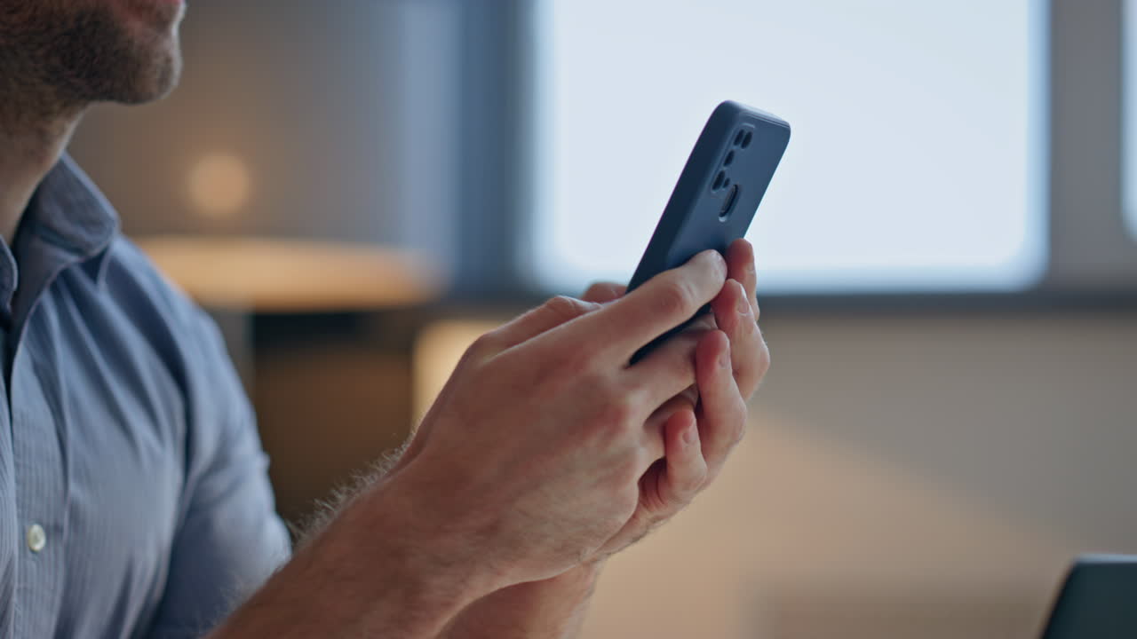 Closeup businessman fingers tapping mobile phone office workplace. Man working