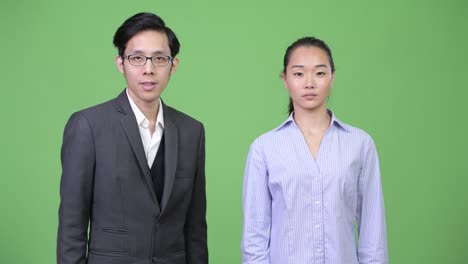 Young Asian business couple giving thumbs up together