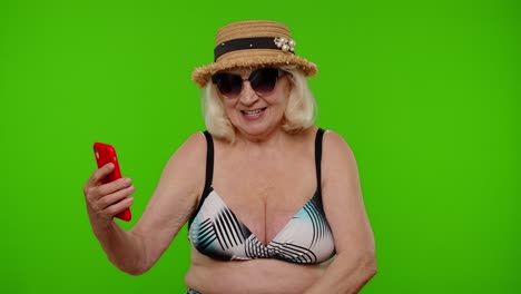 blogger viajera mujer madura con gafas de sol, tomando una foto de retrato selfie, llamada de video en teléfono inteligente