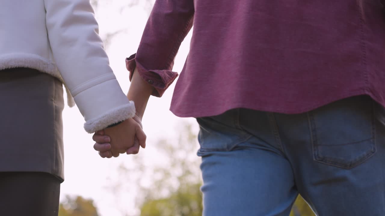 a couple holding hands as they walk.