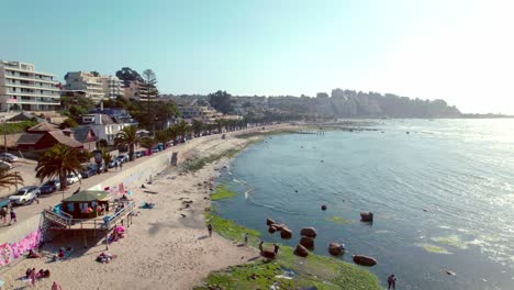 Bird's-eye-view-of-a-small-store-on-the-shore-of-Los-Fósiles-beach-in-Algarrobo,-a-quiet-and-uncrowded-beach-with-shallow-waters-on-a-sunny-day