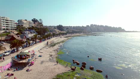 Vista-De-Pájaro-De-Una-Pequeña-Tienda-En-La-Orilla-De-La-Playa-De-Los-Fósiles-En-Algarrobo,-Una-Playa-Tranquila-Y-Con-Poca-Gente-Con-Aguas-Poco-Profundas-En-Un-Día-Soleado