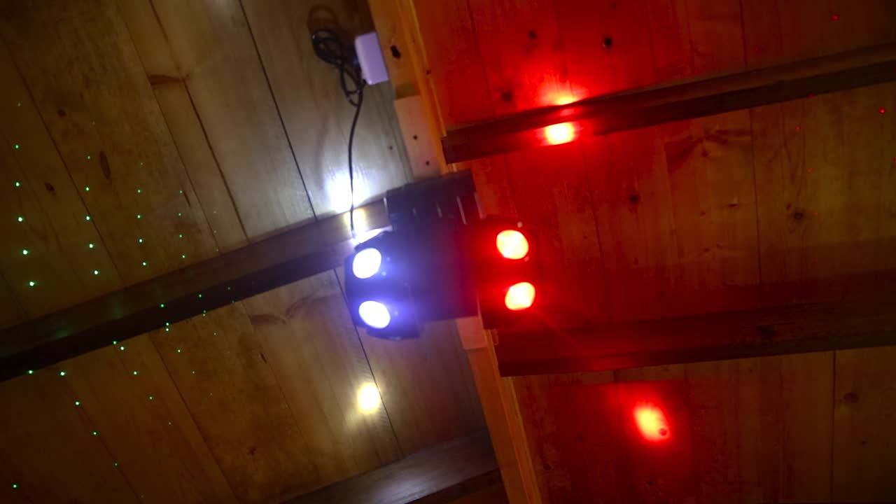 Upward circling shot of colorful spotlights hanging from ceiling of establishment