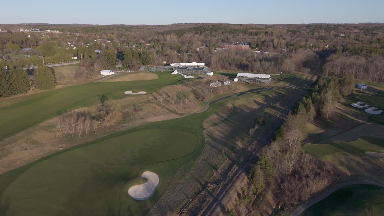 Aerial flyover TPC Toronto at Osprey Valley during sunset time. Empty fields and leafless trees in early spring. Alton,Canada. Rural scenic landscape in the evening. Wide shot.