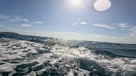 dynamic ocean waves captured from a moving boat in phuket, thailand, under bright sunlight and clear skies