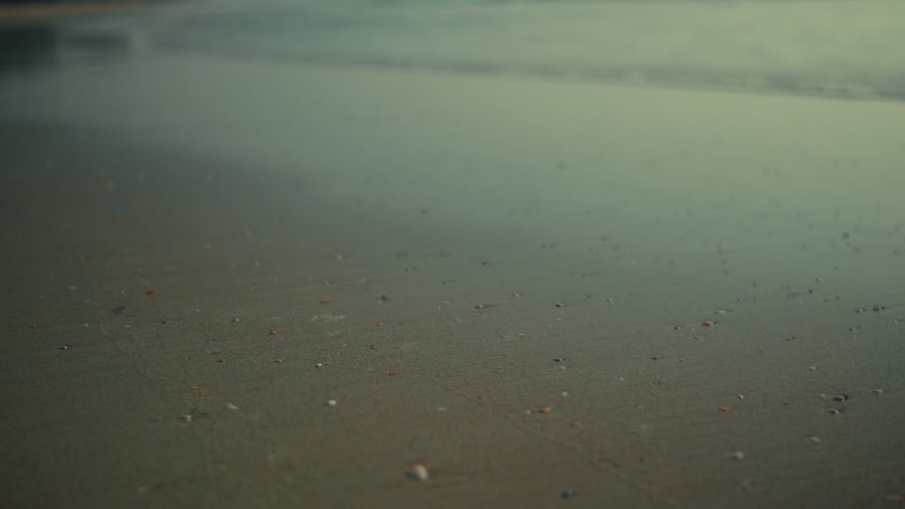Calm sea waves and foam under soft light at dawn on a serene beach