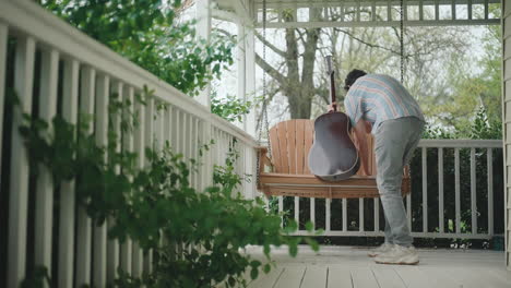 man playing guitar on a porch swing