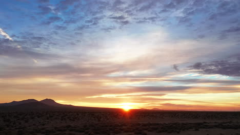 golden sunrise over the barren mojave desert landscape with colorful clouds overhead