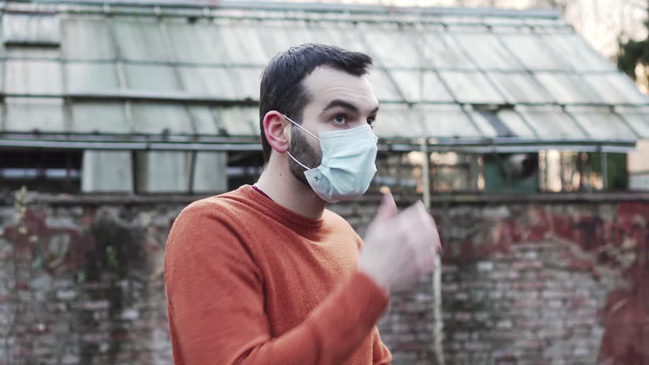 Caucasian man walking, putting on and wearing medical mask, loopable shot