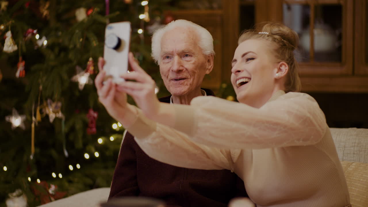 mujer alegre tomando selfie con abuelo durante navidad 3