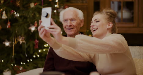 mujer alegre tomando selfie con abuelo durante navidad 3