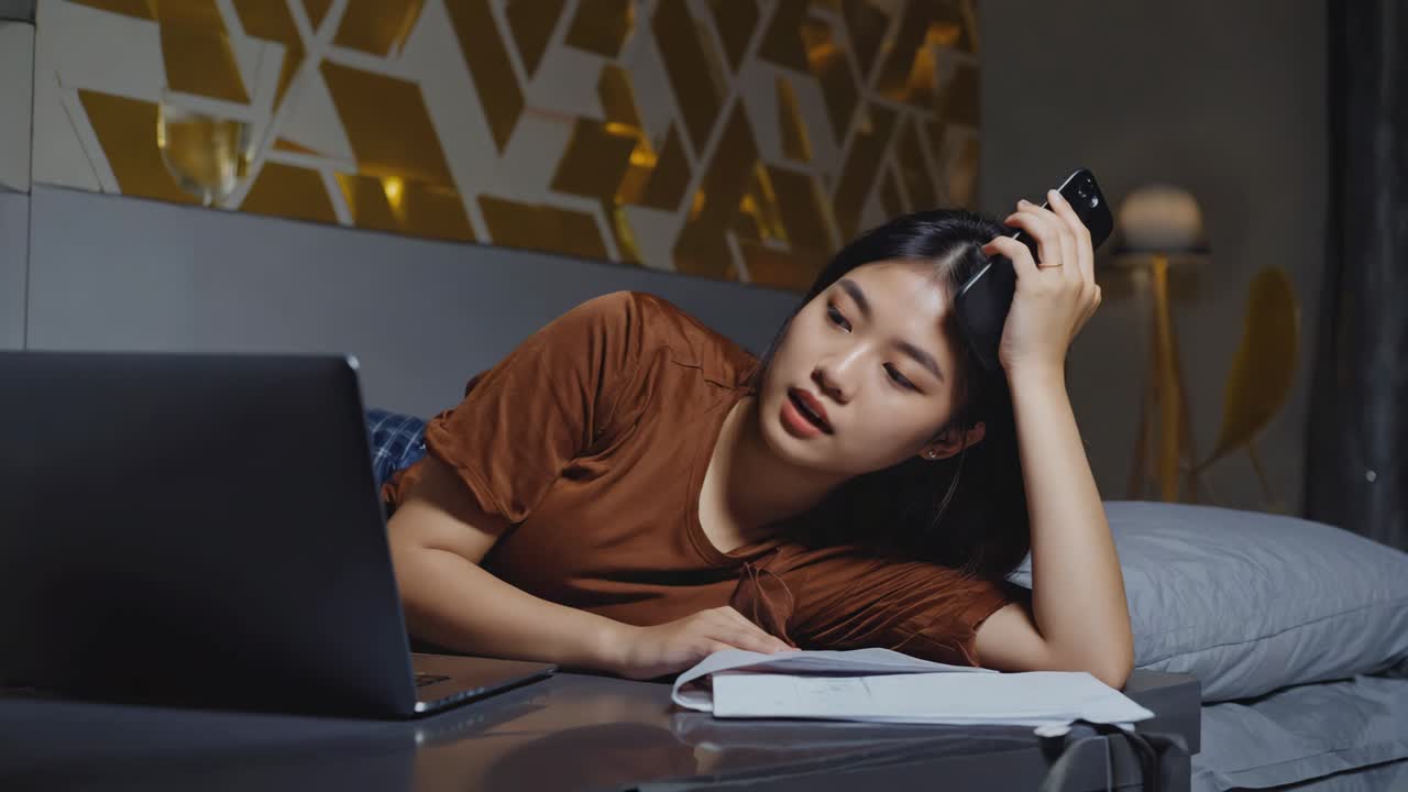 Tired woman working on laptop in bed