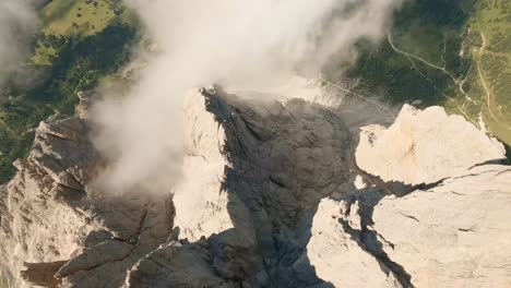 FPV-drone-descends-rapidly,-skimming-Sasslong-mountain-in-Italian-Dolomites,-a-thrilling-proximity-flight-through-a-narrow-canyon-ending-above-lush-spruce-trees