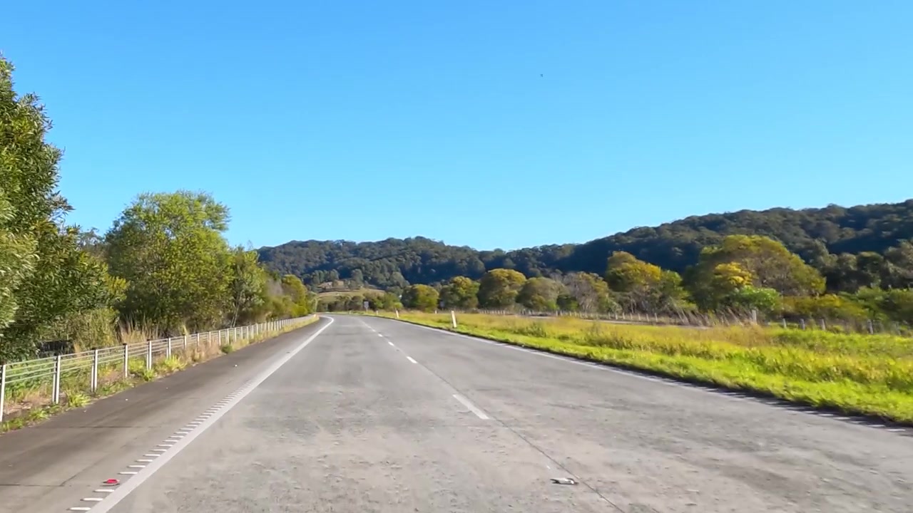 Vista dalla telecamera frontale che viaggia lungo un'autostrada asfaltata attraverso la campagna australiana a Wardell