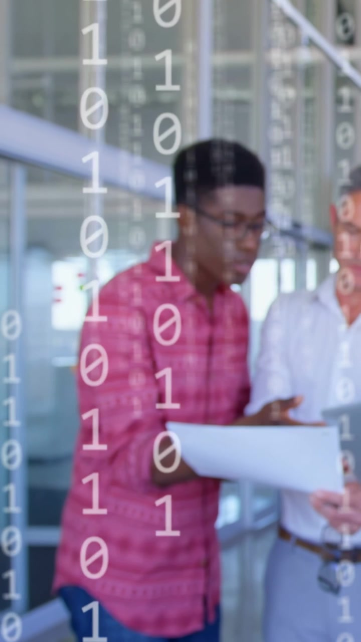 Vertical video: Two men using laptop and docs pointing, showing cyan UI overlay fading for tech