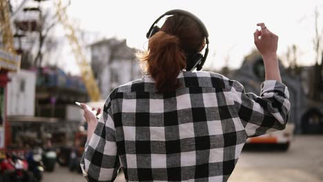 Seguimiento-De-Disparos-De-Una-Joven-De-Cabello-Castaño-Caminando-Por-La-Calle-En-Un-Día-Soleado-Con-Auriculares.-Bailando-Y-Dando-Vueltas.-Feliz-Y-Despreocupado