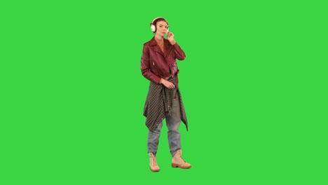 cool rocker girl listening to music in headphones on a green screen, chroma key