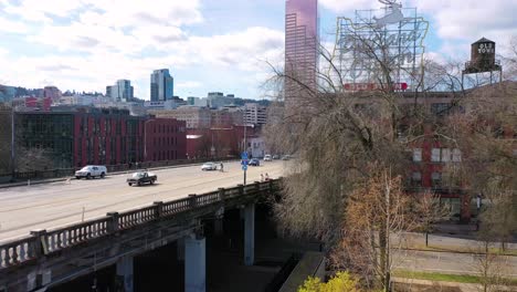 Rising-aerial-past-cherry-trees-reveals-Portland-Oregon-stag-deer-sign-and-downtown-cityscape-and-business-district-1