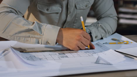 vista de cerca de las manos del arquitecto árabe dibujando un plan de construcción con un lápiz y una regla en el escritorio mientras trabaja en el nuevo proyecto