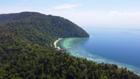 rising aerial view of exotic secluded bay of remote tropical island covered in dense rainforest in raja ampat, west papua, indonesia