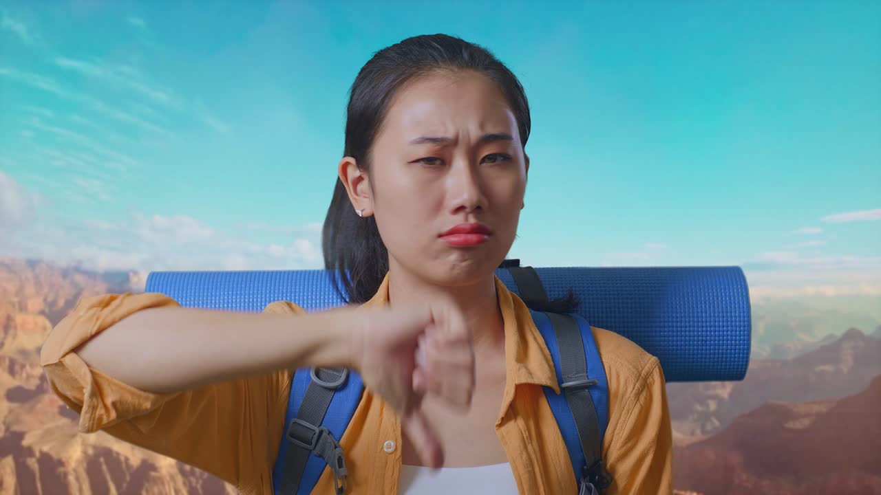 Close Up Of Asian Female Hiker With Mountaineering Backpack Showing Thumbs Down Gesture While Traveling At The Top Of Mountain