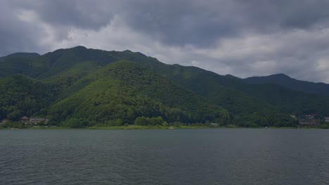 Atraviese-El-Sereno-Lago,-Donde-La-Vista-Se-Despliega-Con-Colinas-Verdes-Que-Caen-En-Cascada-Hacia-Las-Aguas-Japonesas-Desde-El-Mirador-Del-Barco-Durante-Un-Día-Nublado.