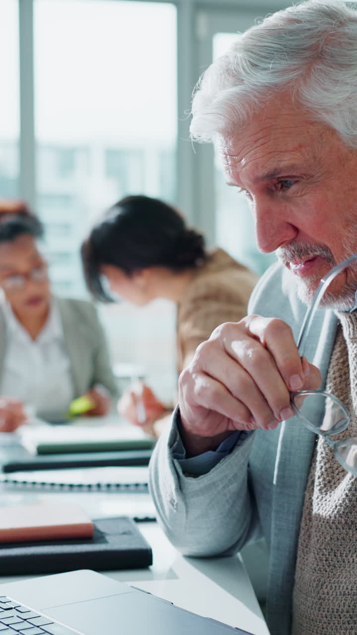 Focused Senior Businessman Working on Laptop in a Bright Office