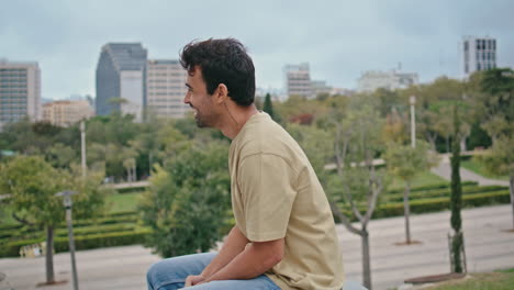 cheerful man ending call at city park bench closeup. smiling spanish guy hung up