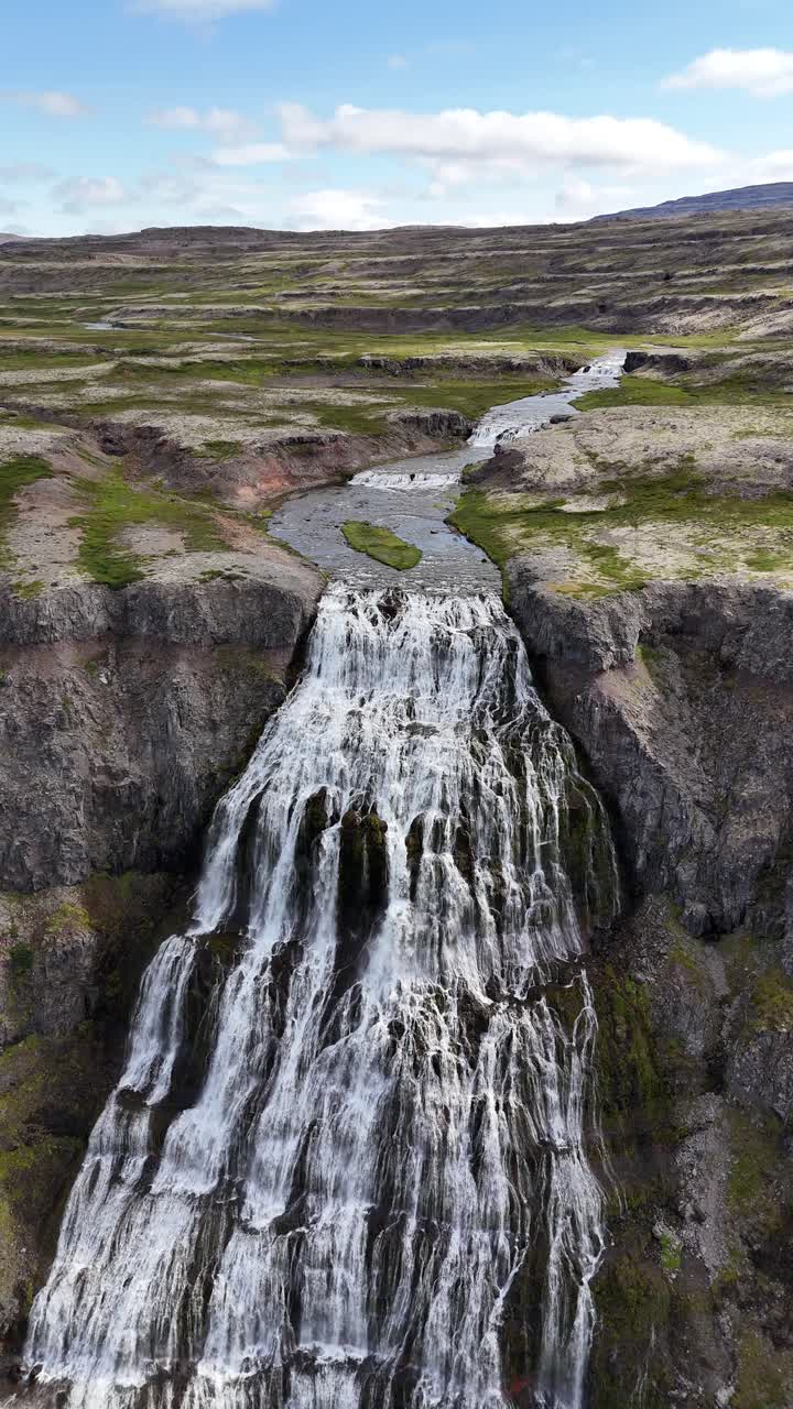 Aerial view of the breathtaking Hrisvaosfoss waterfall in Iceland, vertical video pullback.