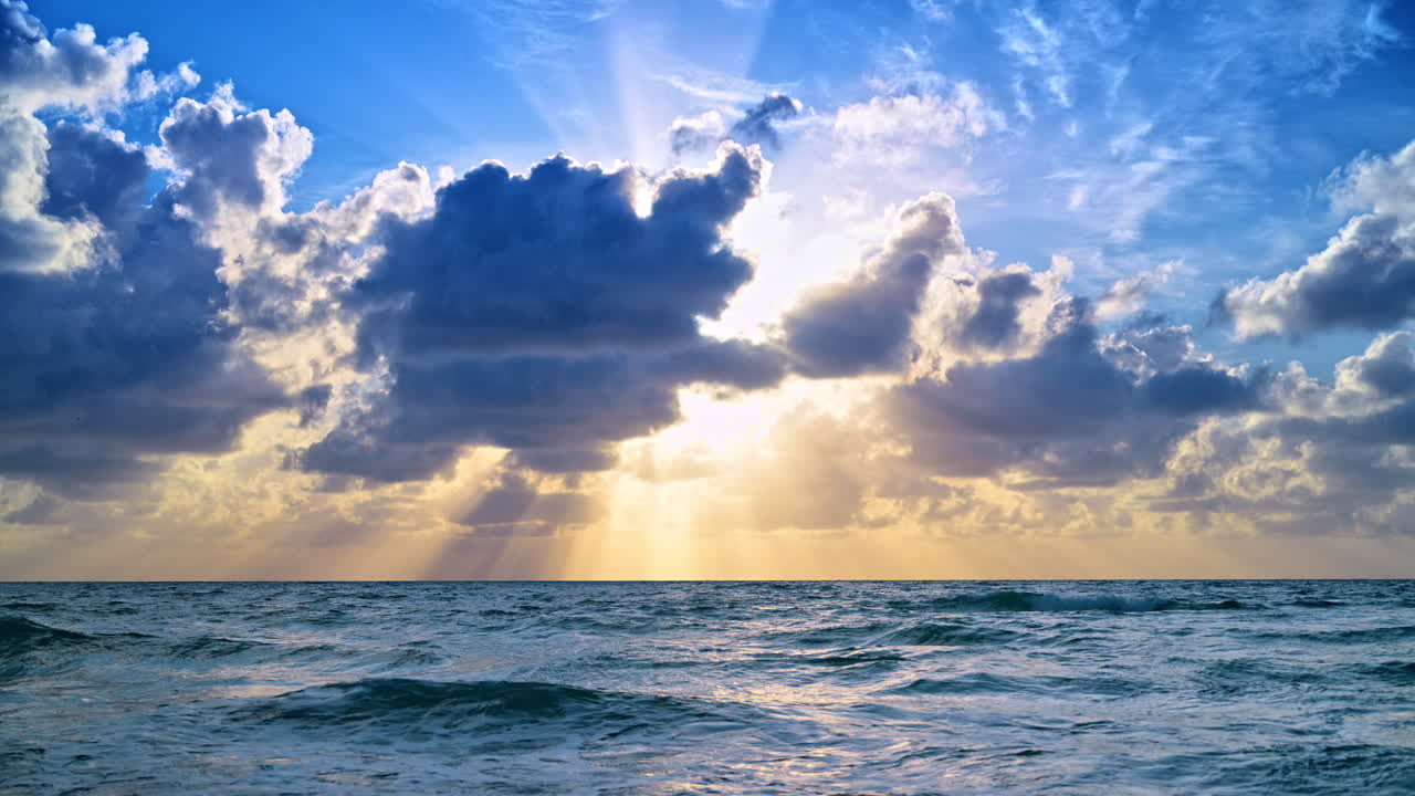 Raggi di sole tra le nuvole sull'acqua dell'Oceano Atlantico. Raggi di luce che splendono da dietro nuvole scure sull'orizzonte marino durante le ore del mattino o della sera.