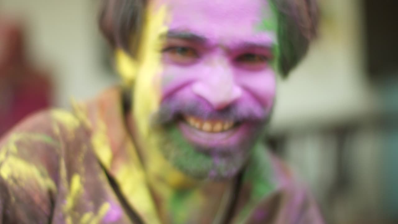 Indian man close-up of face smeared with bright Holi colors