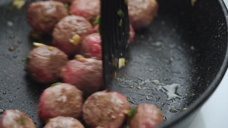 unrecognizable person cooking meatballs on frying pan with oil